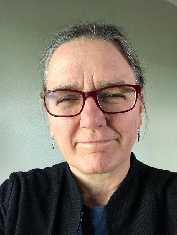 Head shot of myself - a white woman with brown eyes.  Pronouns: she/her/hers.  I am smiling and wearing thick rimmed glasses, Brown turning gray very thin, straight hair is pulled back.